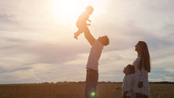 istock Young father tosses son and mother with elder boy looks 1336429463