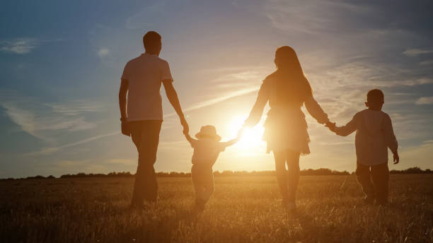 istock Family with children walks along fields at back setting sun 1336429471