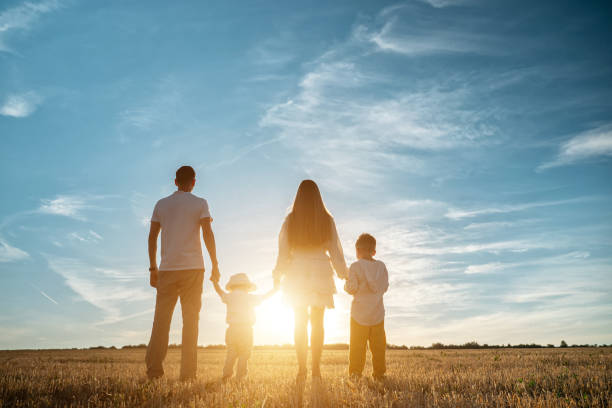 istock Family with children walks along fields at back setting sun 1336429488
