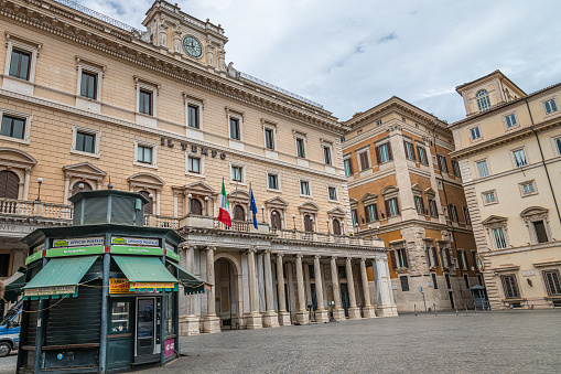 Rome, Italy - 17.07.2021: City street and people on piazza square by Palazzo Wedekind palace with entrance exterior and flags