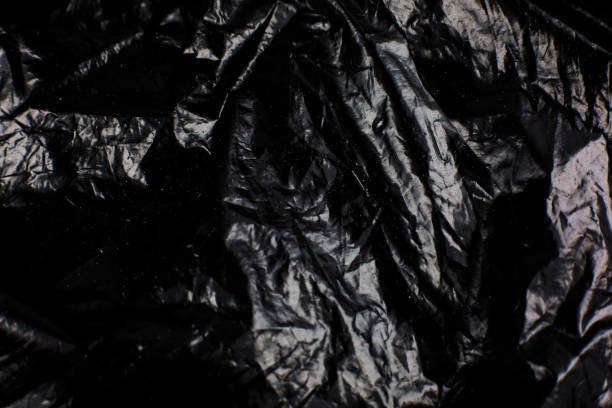 istock Crumpled Black Plastic Bag texture background. Glossy polyethylene overlay 1336433025