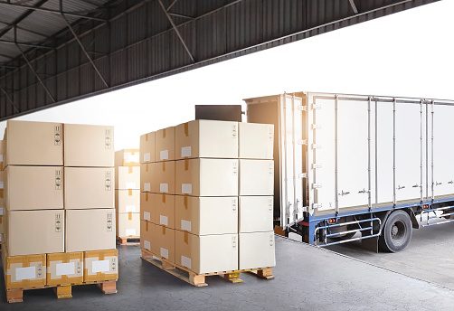 Stack of Package Boxes on Pallets Load with Shipping Cargo Container. Truck Parked Loading at Dock Warehouse. Delivery. Warehouse Logistics. Cargo Freight Truck Transportation.