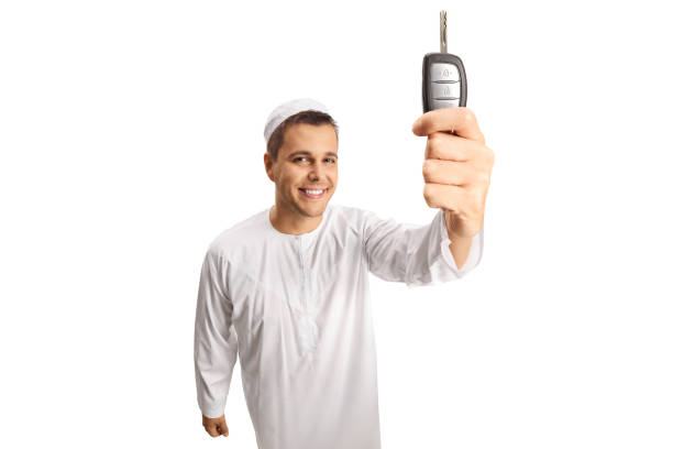 istock Young man in white ethnic clothes holding car keys 1336434637