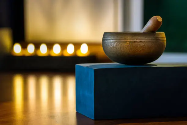 singing bowl on blue soft block on blured candle light background in yoga room