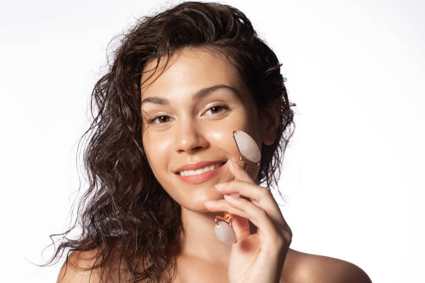 niña masajeando cara por gua sha jade roller. masaje facial de autocuidado, procedimiento de cuidado de la piel de levantamiento antienvejecimiento - health spa women spa treatment massager fotografías e imágenes de stock