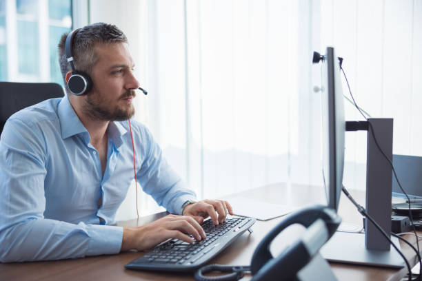 istock Businessman in the office using computer and headset on conference call 1336442149