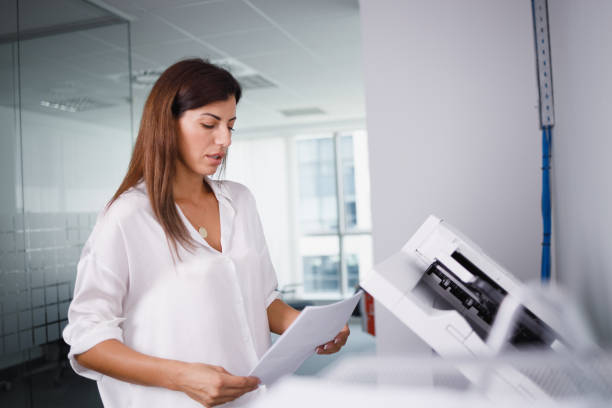 istock Female office clerk holding documents for making copies on xerox 1336442552