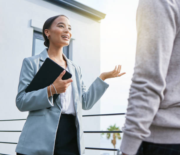 Shot of a young female real estate agent showing a client a house I'll give you a quick tour estate agency stock pictures, royalty-free photos & images