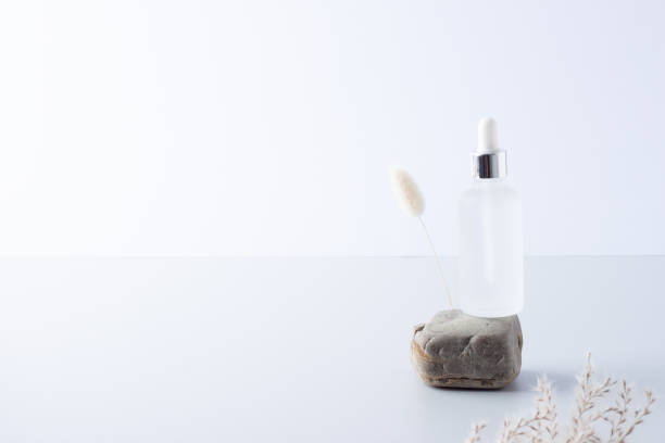 istock Cosmetic bottle with flowers and stone on grey background. Close up, copy space 1336444902