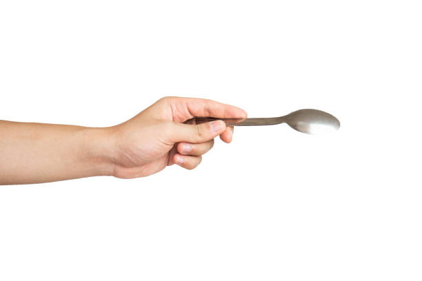 istock Close up of hand holding stainless spoon isolated with white background 1336445021
