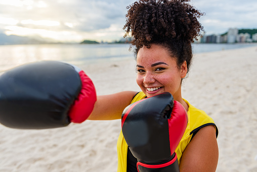 Woman in sportswear wearing boxing gloves on a beach