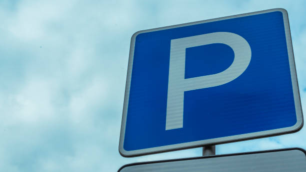 istock Blue road sign with letter P on rectangular plate isolated against a blue sky. Parking symbol on a cloudy blue sky background. Space for text. 1336451629