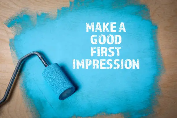 Photo of Make a Good First Impression. Paint roller with blue paint on a wooden surface