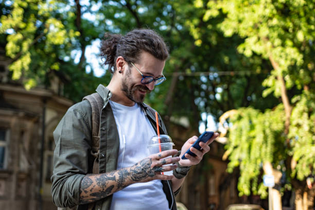 istock Young modern man using smart phone on the city street 1336453152