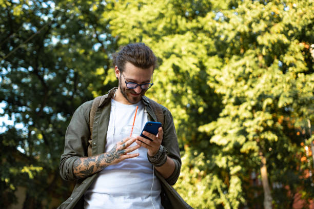 istock Young modern man using smart phone on the city street 1336453156