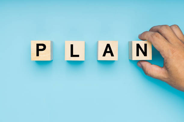 plan letter on wood block with hand holding on blue background