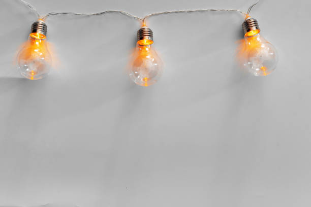 istock Light bulbs illuminated garland on light gray background 1336459067
