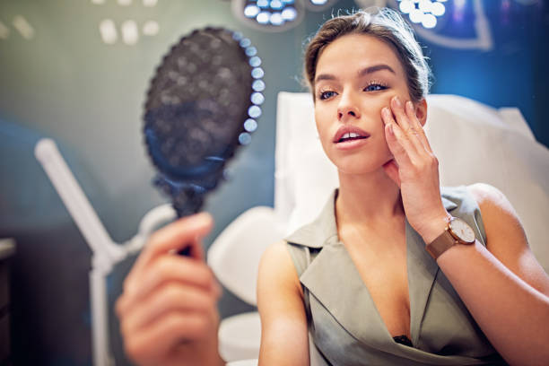 젊은 여자 는 미용 치료 절차 후 거울에 그녀의 얼굴을 보고 - plastic surgery botox injection face lift nose job 뉴스 사진 이미지