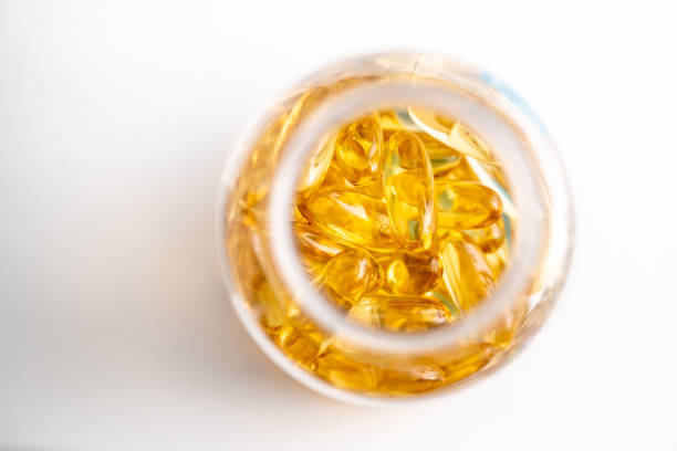 fischöl omega 3 abstrakter gelber hintergrund - cod liver oil fish oil vitamin e vitamin pill stock-fotos und bilder