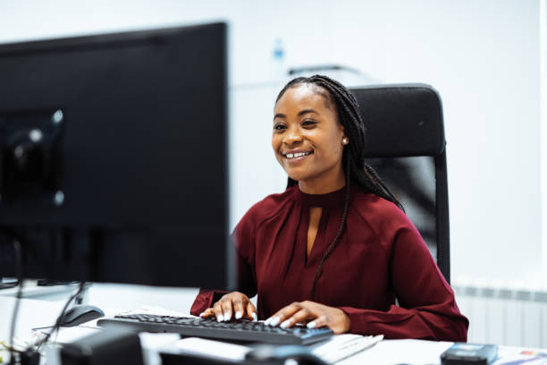 istock Smiling African woman working in office on desktop computer 1336462287