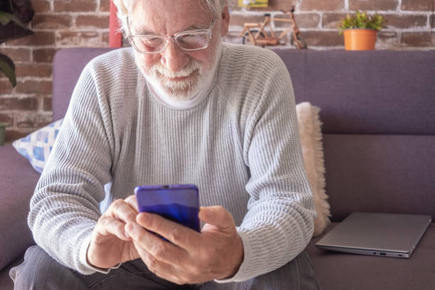 istock Senior man sitting on  sofa at home using mobile phone. Retired leisure people concept 1336463107