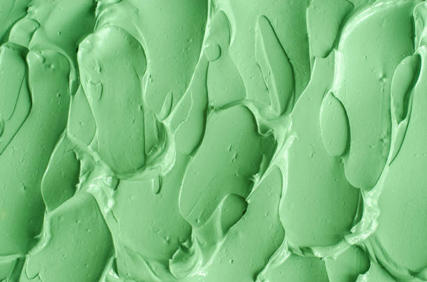 istock Green cosmetic clay (cucumber facial mask, avocado face cream, green tea matcha body wrap) texture close up, selective focus. Abstract background with brush strokes. 1336463280