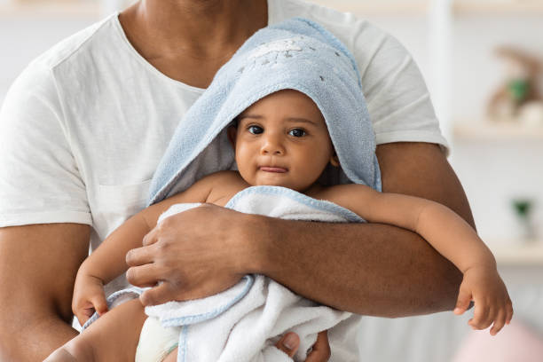 adorable bebé negro bebé en toalla relajante en los brazos del padre después del baño - bebe bañandose fotografías e imágenes de stock