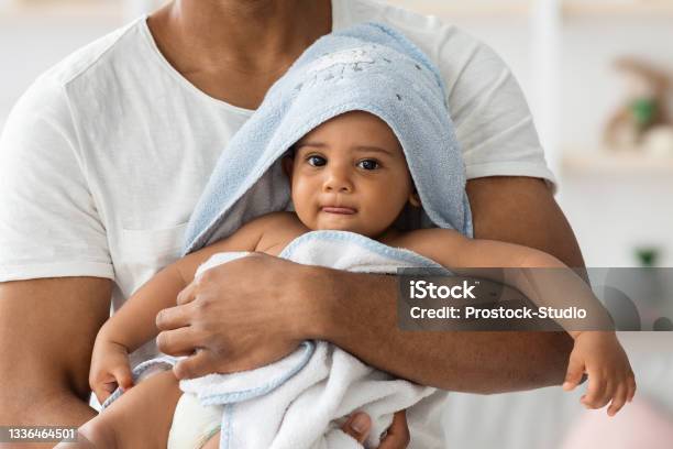 Adorable Black Infant Baby In Towel Relaxing In Fathers Arms After Bath Stock Photo - Download Image Now