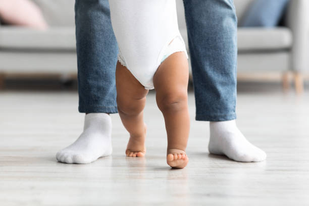 крупный план ног отца и маленького ребенка. мужчина помогает ребенку делать первые шаги - steps baby standing walking стоковые фото и изображения