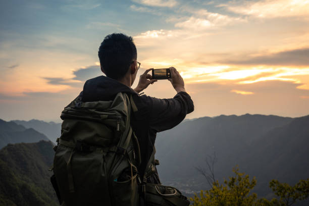 istock Man photograps mountain sunset by mobile phone 1336464683