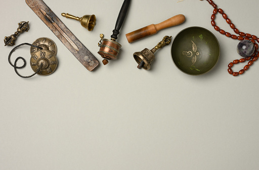 Tibetan singing copper bowl with a wooden clapper on a gray background, objects for meditation and alternative medicine, top view, copy space