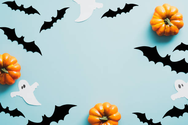 istock Halloween flat lay composition with bats, ghosts, pumpkins on blue background. Vintage style. Happy Halloween holiday concept. 1336464737