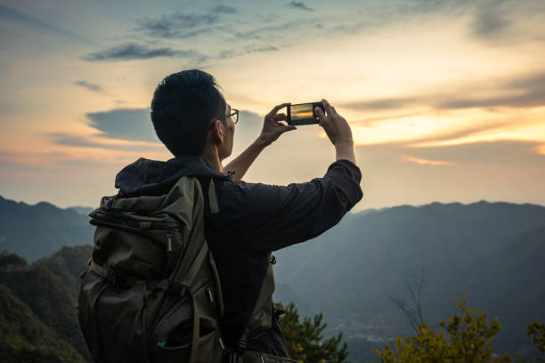 istock Man photograps mountain sunset by mobile phone 1336464876