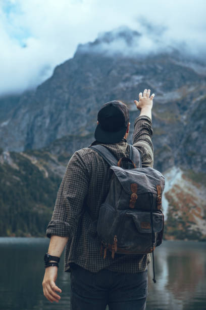 istock man with backpack at lake in mountains hiking concept 1336464957