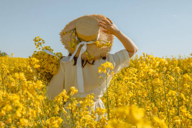istock woman standing in rapeseed field rear view from behind 1336464968
