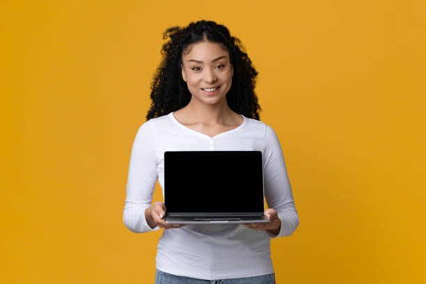 istock Online Offer. Beautiful Smiling Female Holding Laptop Computer With Black Blank Screen 1336466001