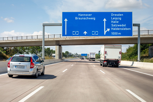 Magdeburg, Germany - August 16, 2021: Traffic on german Autobahn A2 nearby Kreuz Magdeburg in Saxony-Anhalt. The Bundesautobahn 2 (abbreviated as BAB 2 or A 2) is a German highway that connects the Ruhr area in the west to Berlin in the east of Germany. Kreuz Magdeburg connects the A2 with the A14 (Wismar-Magdeburg-Dresden). Some road users in the background.