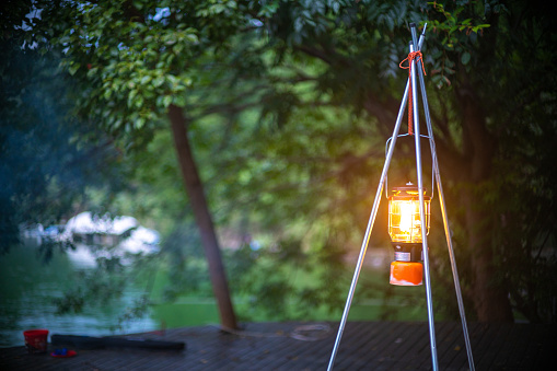 A led camping lamp on an awning pole in the woods at camping site.