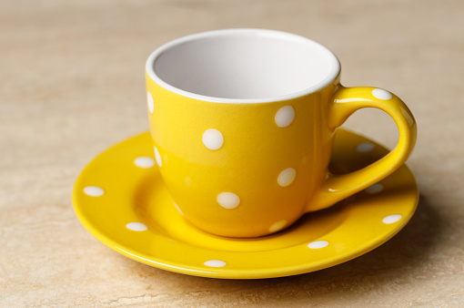 Yellow polka dot teacup and saucer on a table.