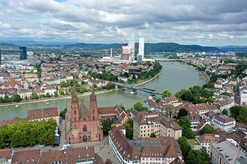 Basel City panoramic wiev over the old town with Basel Minster and several modern skyscrapers in the background. The high angle image was captured during summer season.