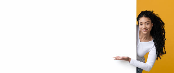 istock Look At This. Smiling Young Black Lady Pointing At White Advertisement Board 1336475637
