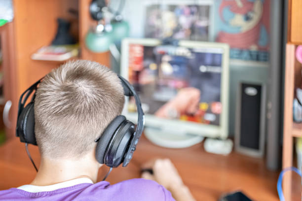 istock A teenage boy, a young man playing video games on a computer, using technology, wearing headphones, using a computer.A young man, a teenager using technology. He plays video games. Using headphones 1336478220