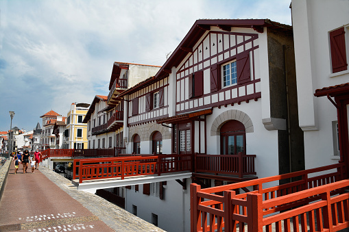 Saint Jean de Luz, French Basque Country, France - August 9, 2020: typical houses with their bridges on the promenade of Saint Jean de Luz, with tourists walking on a summer day.