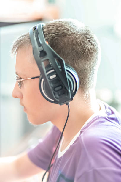 istock A teenage boy, a young man playing video games on a computer, using technology, wearing headphones, using a computer.A young man, a teenager using technology.Using headphones.Back to school 1336478412