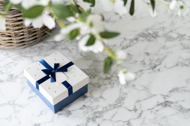 istock Gift box with ribbon and bow under lucious flowers 1336479120