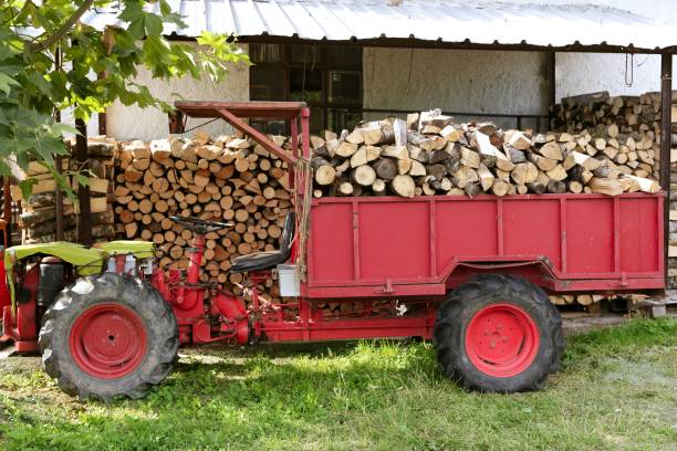 Firewood working tractor in red color with stacked wood