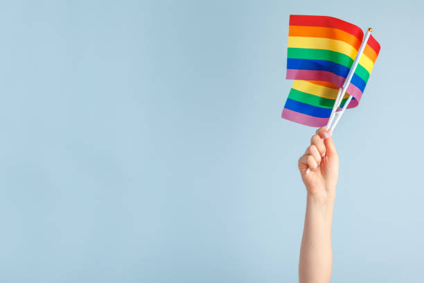 istock Gay flags in women's hand on grey background 1336480542
