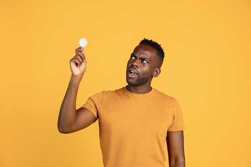 Incredibly strange. Portrait of African young man in casual clothes isolated on yellow color studio background. Concept of human emotions, facial expression, youth, sales, diversity. Copy space for ad.