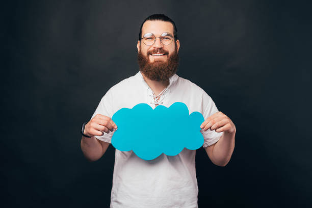 istock Young bearded man is holding a blue paper cloud. 1336481337