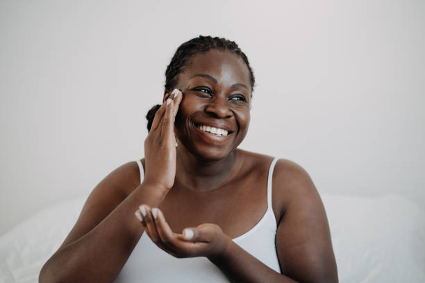 soins de la peau à l’aide de crème cosmétique pour la peau femme à la peau noire - skin cream photos et images de collection